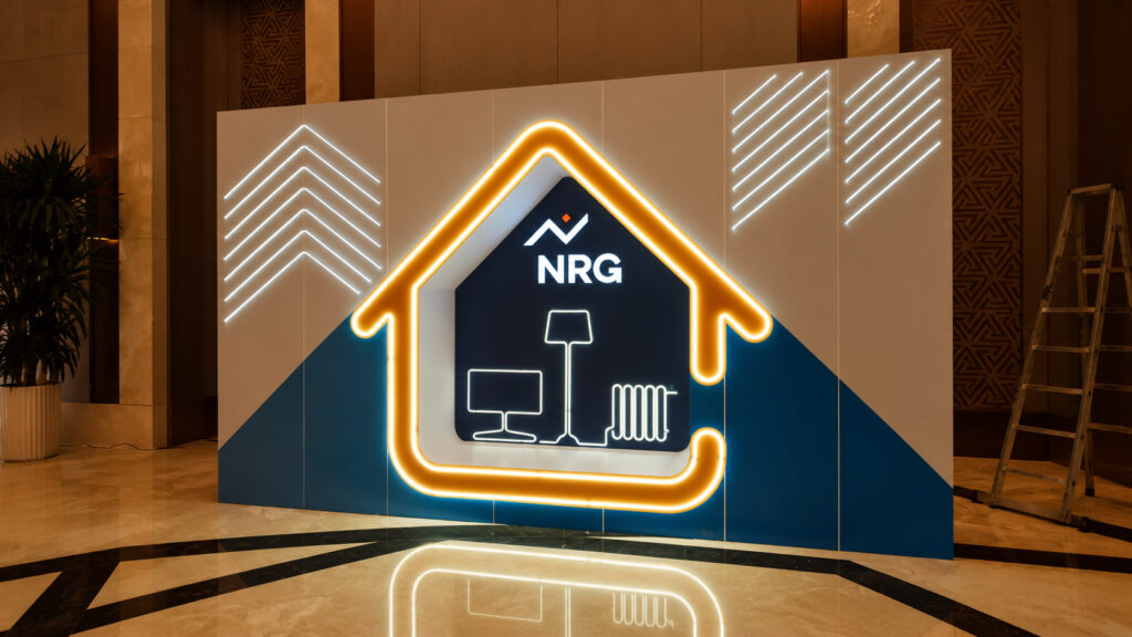 Пресс-вол NRG 2023 с неоновым силуэтом дома и встроенным логотипом